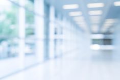 blurry image of an empty hallway with white walls and windows in the background,