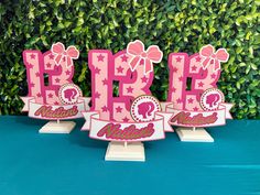 three pink happy birthday cake toppers on a blue table