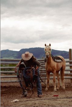 a man in cowboy gear standing next to a horse