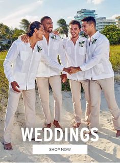 three men in white shirts and tan pants are standing on the beach with their arms around each other