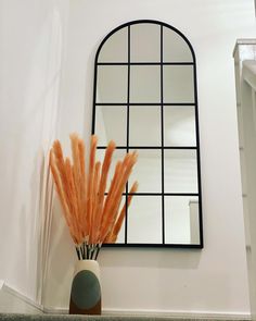 a vase filled with orange flowers next to a mirror