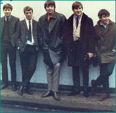 the beatles are posing for a photo in front of a wall