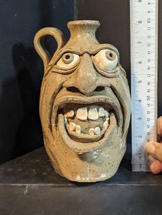 a clay face is shown next to a measuring ruler with it's mouth open