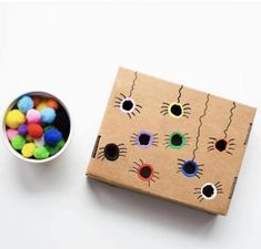 a box filled with colorful pom poms next to a bowl of colored balls