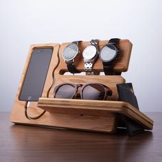 three watches and two cell phones in a wooden display case on a table with an iphone