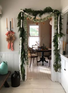 an archway decorated with greenery and candles in the dining room is seen from the entry way