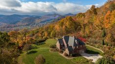 an aerial view of a home surrounded by mountains and trees in the fall with colorful foliage