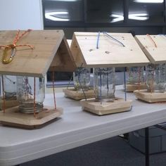 three small wooden houses sitting on top of a table next to each other with wires running through them