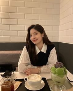 a woman sitting at a table with a cup of coffee and ice cream in front of her