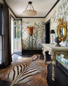 a zebra rug in the middle of a room with an ornate mirror and wallpaper