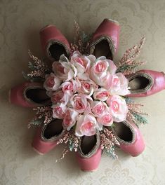 a bouquet of flowers is placed on the wall next to pink ballet shoes and heels