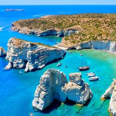 an aerial view of boats in the water near rocky coastlines and cliffs with blue water