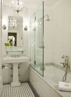 a white bathroom with black and white checkered flooring, chandelier over the bathtub