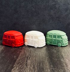 three plastic toy cars sitting on top of a wooden table next to each other in front of a black wall