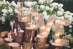 a lighted love sign surrounded by logs and candles