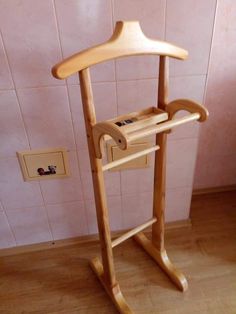 a wooden coat rack in the corner of a room with pink tiles on the wall