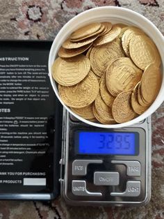 a white bowl filled with gold coins next to a digital scale