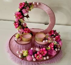 a pink hat with flowers and pearls on it sitting on top of a white table