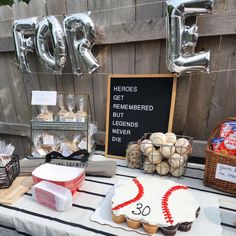 a table topped with cakes and cupcakes covered in frosting next to balloons