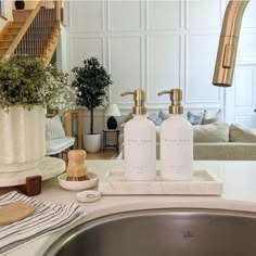 a bathroom sink with soap and lotion bottles on it next to a living room