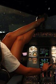 a woman sitting in the cockpit of an airplane with her feet up on the controls