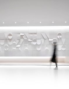 a person walking past a white wall with letters on it