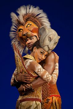 a man and woman in costume hugging each other with their faces painted to look like animals