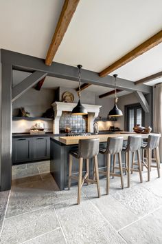 a kitchen with an island and bar stools in the middle of it, surrounded by wooden beams