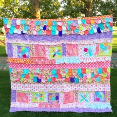 a colorful quilt hanging from the side of a tree