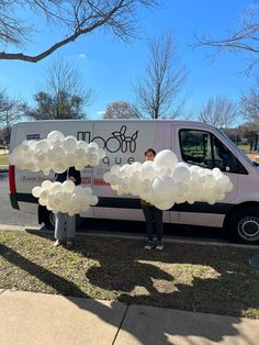 two people standing next to a van with balloons in the shape of letters on it