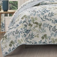 a bed covered in a blue and green floral comforter