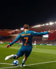 a man kicking a soccer ball on top of a field