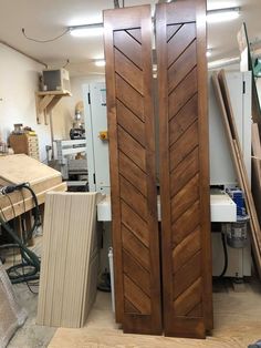 two large wooden doors in a room with many pieces of wood on the floor next to them