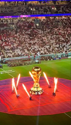 the world cup trophy is lit up in front of an audience at a soccer game