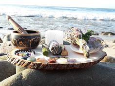 there is a bowl on the beach with seashells and other items around it