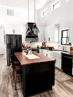 a kitchen with black and white appliances and wood flooring, along with an island in the middle