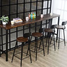 four stools and a table in front of a brick wall with books on it