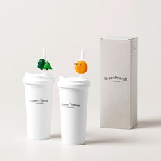 two coffee cups with strawberries on top next to an orange and green friend box