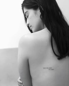 the back of a woman's shoulder with a small tattoo on her left side