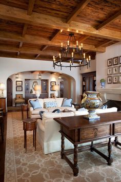 a living room filled with furniture and a chandelier hanging from the wooden ceiling