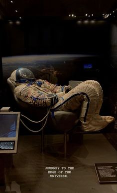 an astronaut's suit and helmet on display in a museum case with information about the space shuttle