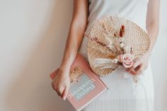 a woman in white holding a straw hat and a pink box with flowers on it