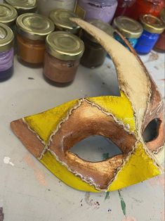 a yellow mask sitting on top of a table next to paint cans and other items