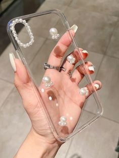 a hand holding a clear case with pearls on it