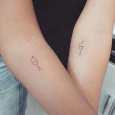 two people with tattoos on their arms holding each other's hands and one has a wine glass in it