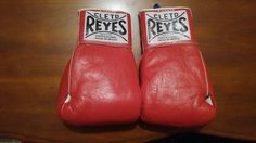 two red boxing gloves sitting on top of a wooden table