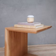 a stack of books sitting on top of a wooden table next to a jar of cream