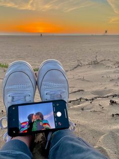 someone is taking a photo with their cell phone on the beach at sunset or sunrise