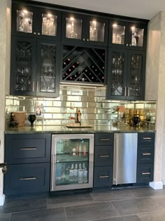 a wine cooler in the middle of a kitchen with stainless steel appliances and glass cabinets