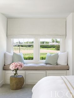 a window seat with pillows and flowers on it